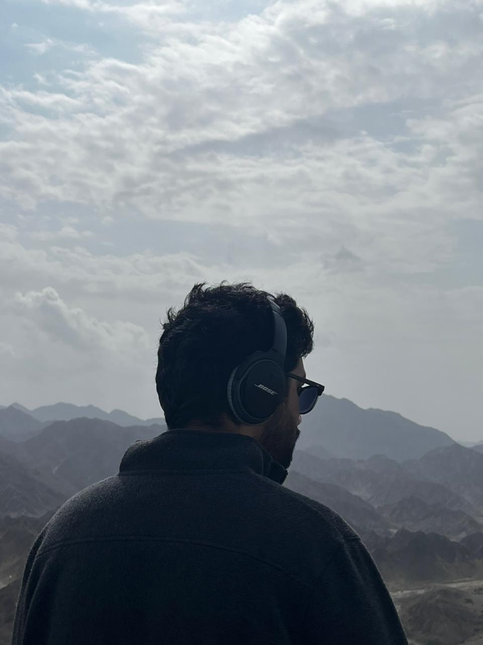 Abdullah Kamran in headphones looking out over a mountain range